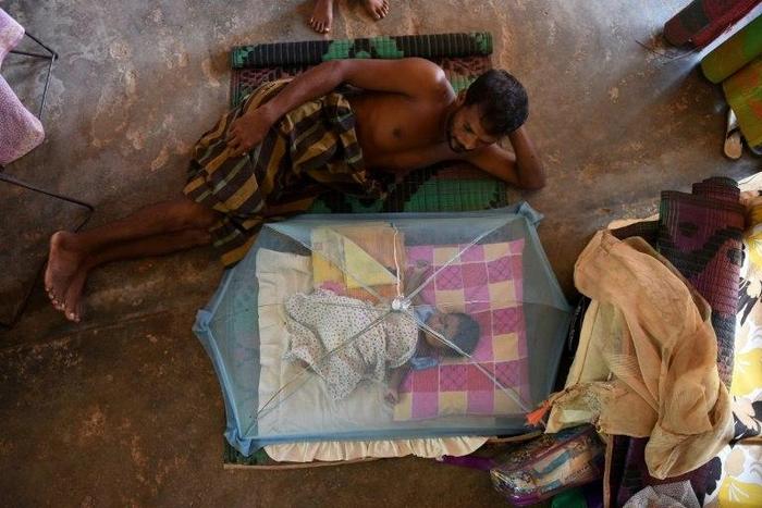 A Sri Lankan child and man rest at a relief camp after being evacuated following flooding Sri Lanka that killed more than 200 people