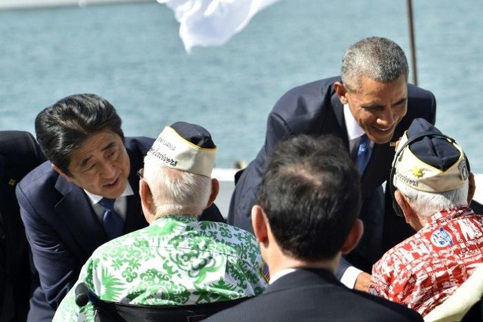 US President Barack Obama (R) and Japanese Prime Minister Shinzo Abe greet veterans at Kilo Pier overlooking the USS Arizona Memorial at Pearl Harbor in Honolulu, Hawaii on December 27, 2016