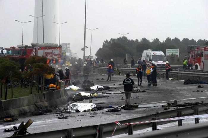 Firefighters work at helicopter crash site in Istanbul on March 10, 2017 as bodies lie covered with blankets