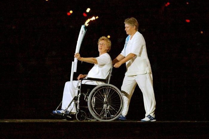 Olympic running legend Betty Cuthbert (L), winner of four gold medals in 1956 and 1964, is escorted by Reelene Boyle as she holds the Olympic torch during the opening ceremony of the 2000 Summer Olympics in Sydney