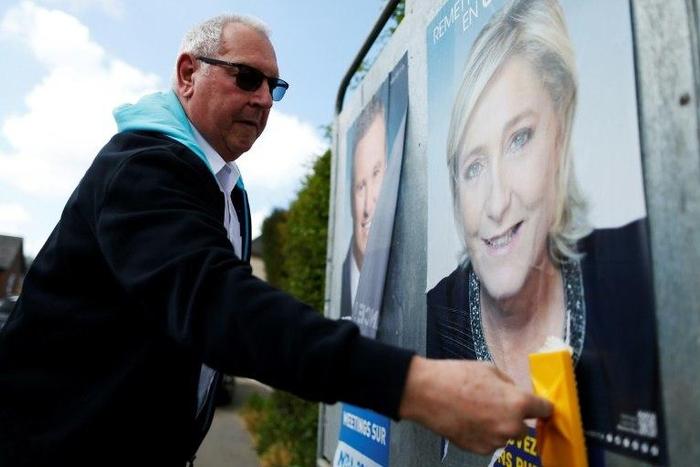 A man puts up a campaign poster for French presidential election candidate Marine Le Pen in the city of Dieppe, northwestern France, on April 14, 2017