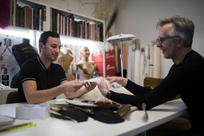 Serkan Cura, left, one of the world's top plumassiers, examines a feather design with Olivier Portais of the French wedding dress label Cymbeline