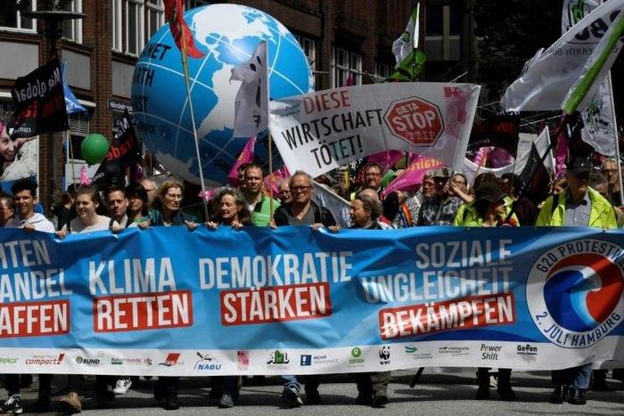 Demonstrators march behind an anti G-20 banner during a demonstration called by several NGOs ahead of the G20 summit in Hamburg on July 2, 2017