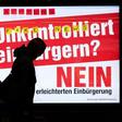 A man walks past an electoral poster by the Committee against Facilitated Naturalization/Citizenship reading "Uncontrolled Naturalisation? No" featuring a woman wearing a niqab, in a train station in Zurich, on February 7, 2017
