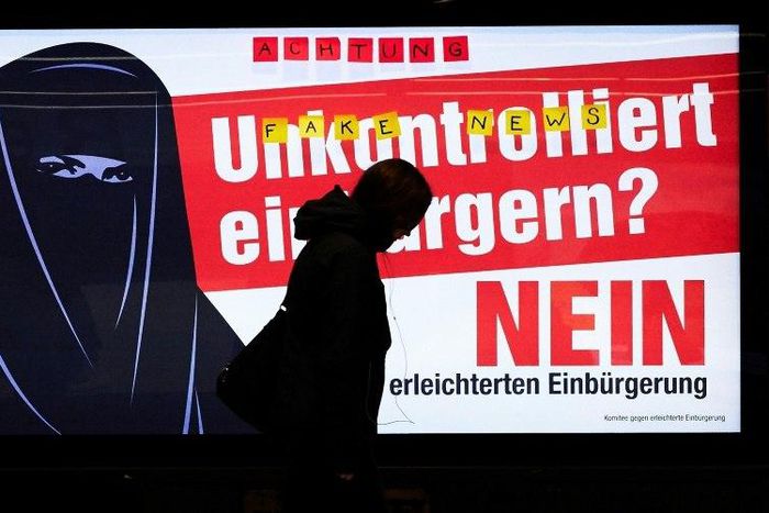 People walk by electoral posters by the Committee Against Facilitated Naturalization/Citizenship reading "Uncontrolled Naturalisation? No" with the illustration of a woman wearing a niqab, in a train station in Zurich, on February 7, 2017