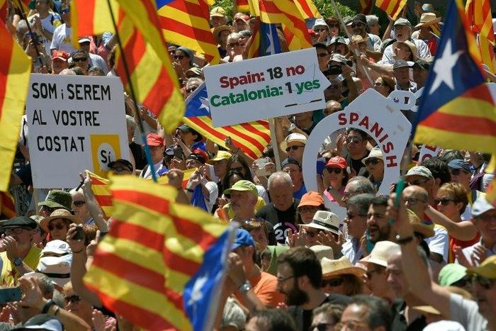 People wave flags and hold up placards during a demonstration dubbed, "Referendum is Democracy" organized by the ANC, AMI and Omnium Cultural, in Barcelona on June 11, 2017 in favour of Catalonia breaking away from Spain