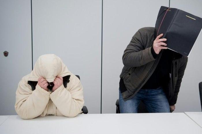 Defendants hide their faces at a regional court in Hildesheim, central Germany, on February 8, 2017