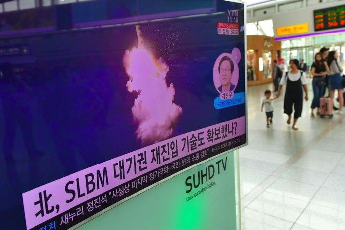 This file photo from August 25, 2016 shows people walking past a television screen at a railway station in Seoul reporting news of a North Korean submarine-launched ballistic missile test