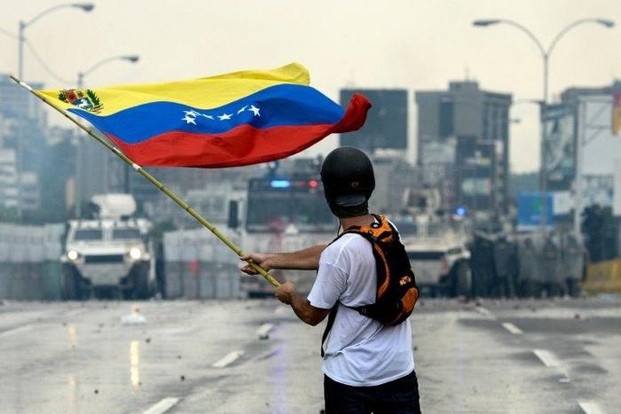 A Venezuelan opposition demonstrator waves a national flag in front of the riot police during a protest against President Nicolas Maduro, in Caracas, on May 8, 2017
