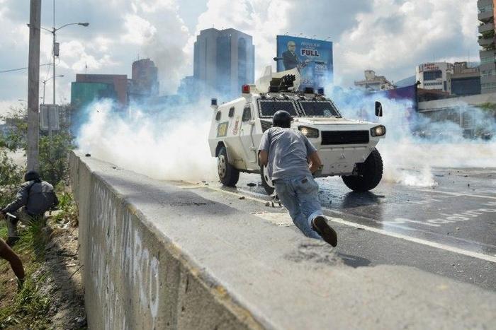 Demonstrators scatter as a National Guard riot control vehicle charges during a protest in Caracas, on May 10, 2017