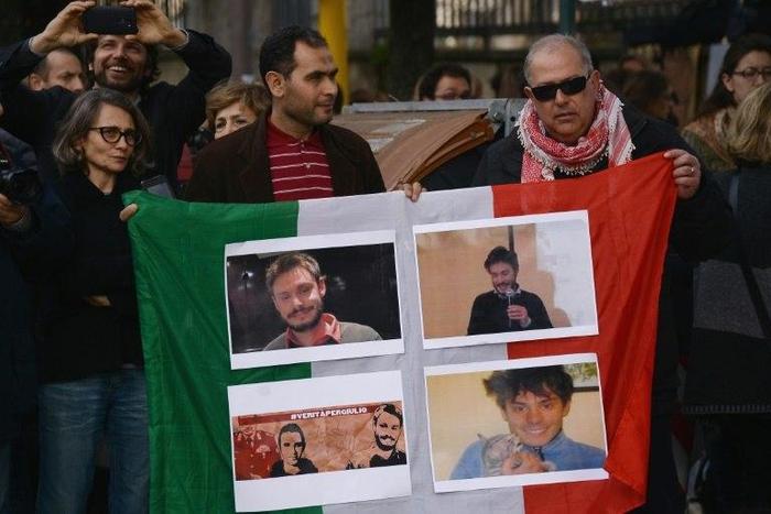 People hold an Italian flag bearing photos of murdered student Giulio Regeni during a protest in Rome on February 25, 2016