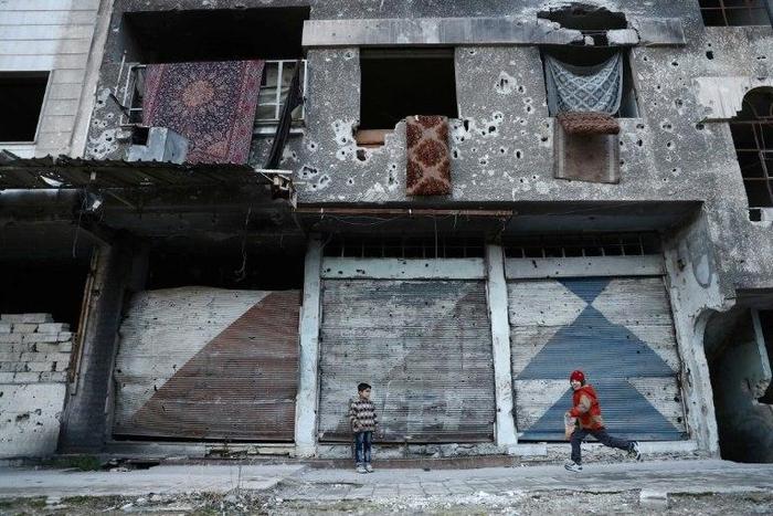 Syrian children play next to a ruined buidling in the rebel-held town of Douma on the eastern outskirts of Damascus on January 9, 2017