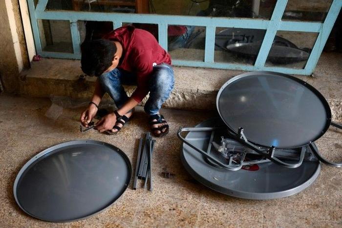 A young Iraqi prepares satellite dishes for sale at a market in east Mosul on April 15, 2017. Since Iraqi forces recaptured the sector from the Islamic State group in January, business has surged