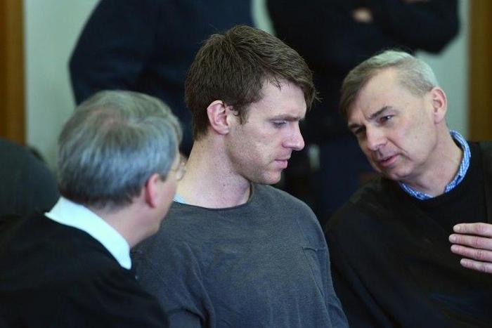 German far-right politician Maik Schneider (centre) talks to his lawyers during his trial in Potsdam, on February 9, 2017