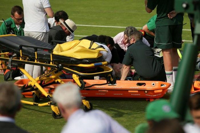 US player Bethanie Mattek-Sands is helped by medics on court after suffering an injury during her women's singles second round match against Romania's Sorana Cirstea on the fourth day of the 2017 Wimbledon Championships July 6, 2017