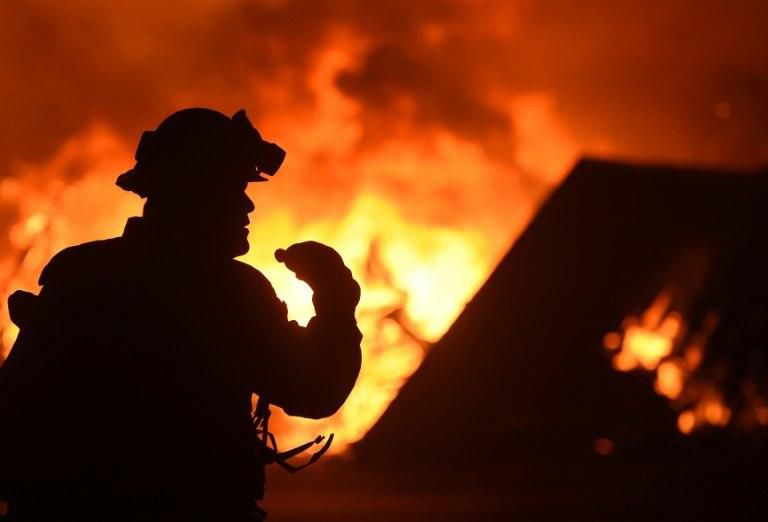 A firefighter drinks water in front of a burning house near Oroville, California on July 9, 2017. Crews are battling the season's first major wildfires since the state's five-year drought ended earlier this year