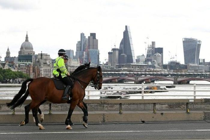 Police on horses ride past a security barrier between the road and the pavement on Waterloo Bridge in London on June 5, 2017, installed in reaction to the recent terror attacks