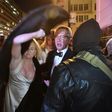 A woman throws her fur coat over her head outside the National Press Club in Washington, DC on January 19, 2017 as protesters shouted at them as they left the "Deploraball" event in honour of new US president Donald Trump