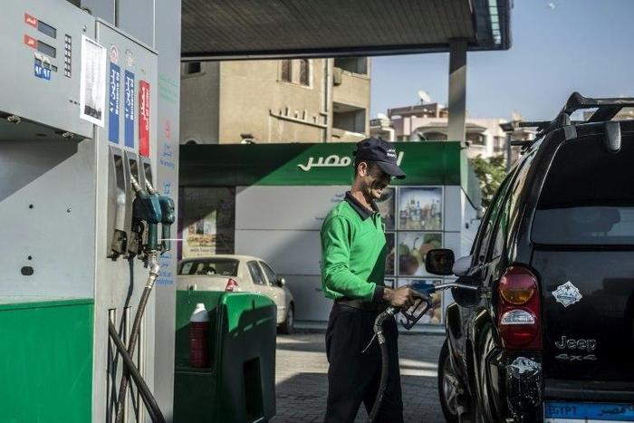 An Egyptian worker fills a customers tank as cars queue at a petrol station in the capital Cairo on November 4, 2016