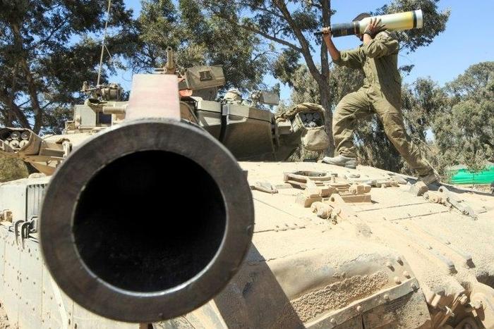 An Israeli soldier carries a shell as he and his comrades prepare their Merkava tanks stationed on the border between Israel and the Gaza Strip on July 31, 2014