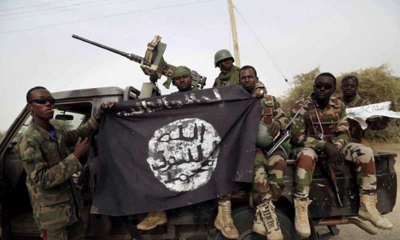 Nigerian soldiers hold up a Boko Haram flag that they had seized in the recently retaken town of Damasak, Nigeria, March 18, 2015. REUTERS/Emmanuel Braun