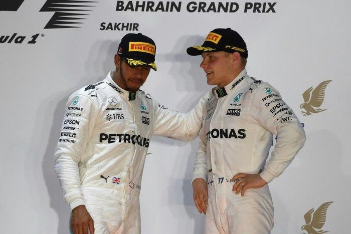 Mercedes' drivers Lewis Hamilton (L) and Valtteri Bottas stand on the podium after Ferrari's Sebastian Vettel won the Bahrain Formula One Grand Prix at the Sakhir circuit in Manama on April 16, 2017