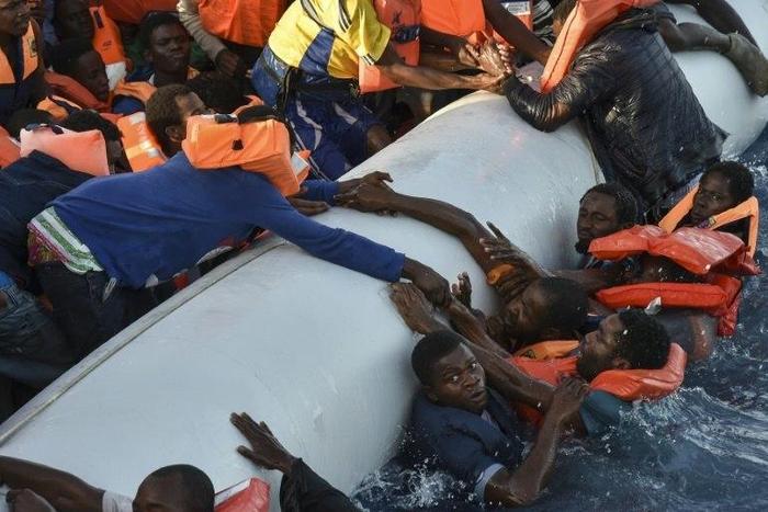 Migrants cling to a boat during a rescue operation off the Libyan coast in November 2016