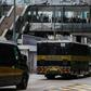 Bystanders watch as a prison van (C) transporting British banker Rurik Jutting, accused of the murders of two Indonesian women, leaves the High Court escorted by a police convoy in Hong Kong in the city's biggest murder case for years