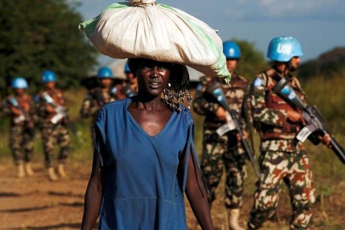 A displaced woman carries goods as UN peacekeepers patrol outside UN Protection of Civilians premises in Juba