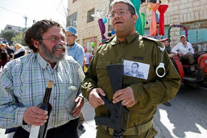 A Jewish settler dressed in military fatigues wears a portrait of Elor Azaria, an Israeli soldier who shot dead a wounded Palestinian assailant, during a parade marking the Jewish holiday of Purim in Hebron on March 12, 2017
