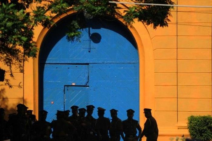 Sri Lankan policemen stand guard in front of protesters outside the main prison in Colombo on August 8, 2011