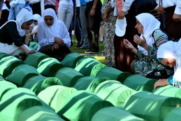 Bosnian women offers prayers near the caskets of 71 victims of the 1995 Srebrenica massacre, at the memorial cemetery in the village of Potocari on July 11, 2017