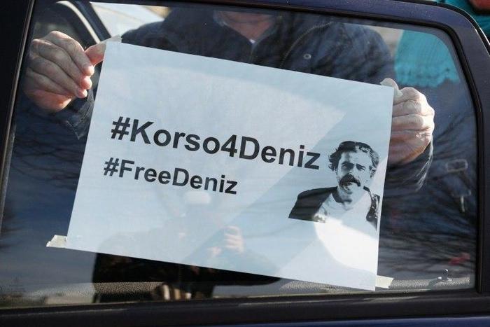 A demonstrator sticks a poster reading "#FreeDeniz" on a car window as he takes part on February 25, 2017 in Floersheim near Frankfurt am Main, western Germany, in a protest to support journalist Deniz Yucel detained in Turkey