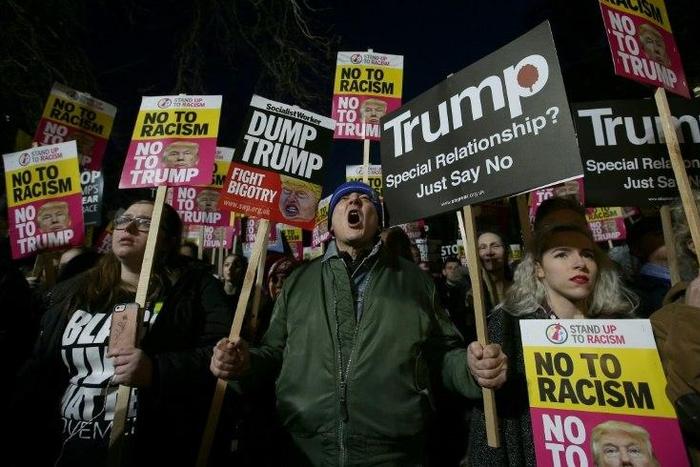 Demonstrators hold placards as they protest outside the US Embassy in London on January 20, 2017