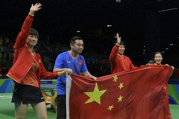 (L-R) China's Ding Ning, coach Kong Linghui, Li Xiaoxia and Liu Shiwen posing with the national Chinese flag after winning gold medals in the women's team final table tennis at the Riocentro venue during the Rio 2016 Olympic Games in Rio de Janeiro
