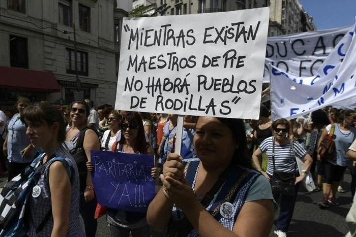 A teacher holds a placard reading "While there are teachers standing, there will be no people on their knees" during a 48-hour nationwide strike demanding pay rises, in Buenos Aires on March 6, 2017