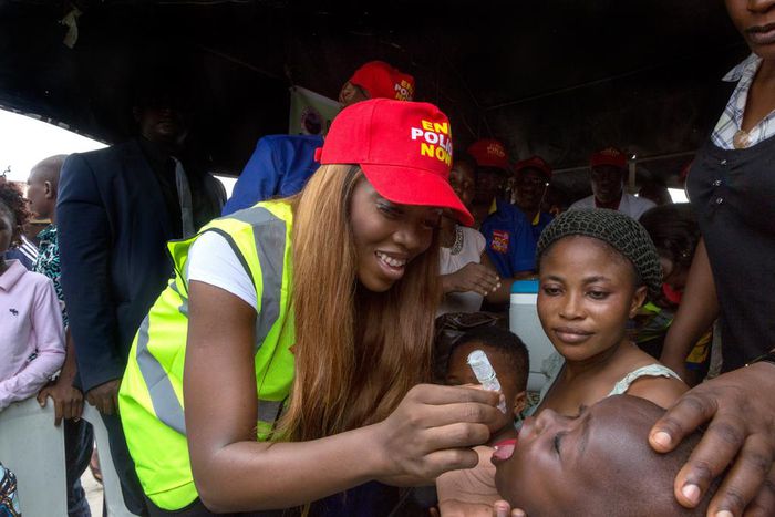 Tiwa Savage giving a child a polio vaccination