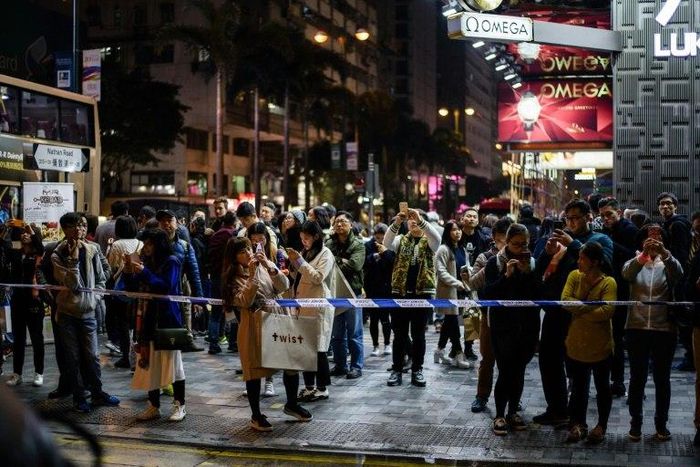 Bystanders gather behind a police cordon outside the Tsim Sha Tsui train station in the Kowloon district of Hong Kong on February 10, 2017, after a fire engulfed a subway train