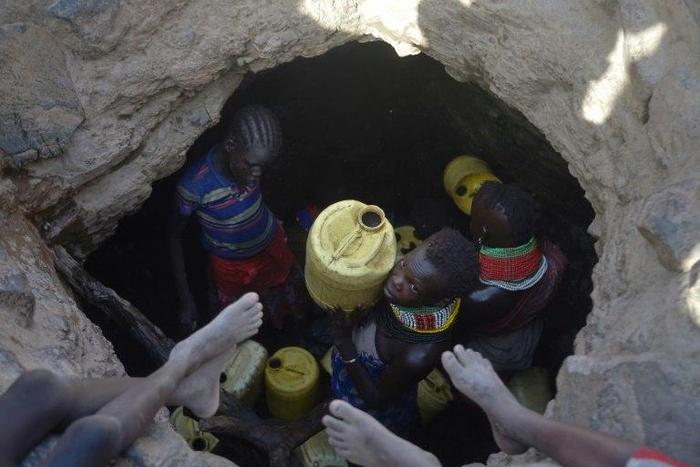 A young girl passes up a jerrycan filled with murky water trickling into a waterhole from underground rocks near Lokitaung in northern Kenya's Turkana county