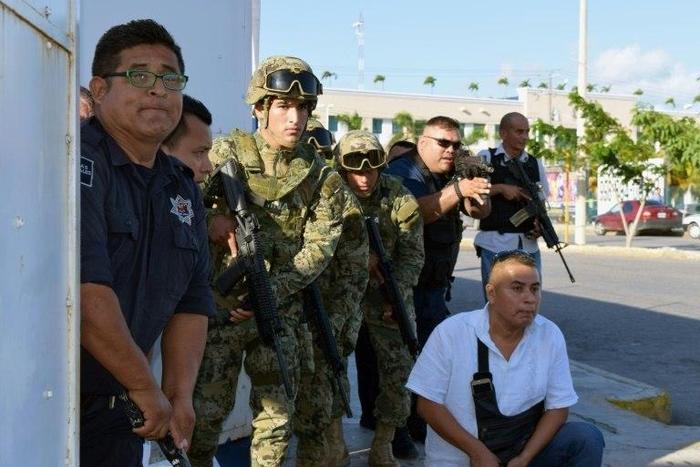 Policemen and soldiers take cover near the building of the Quintana Roo State Prosecution, in Cancun, Mexico, on January 17, 2017