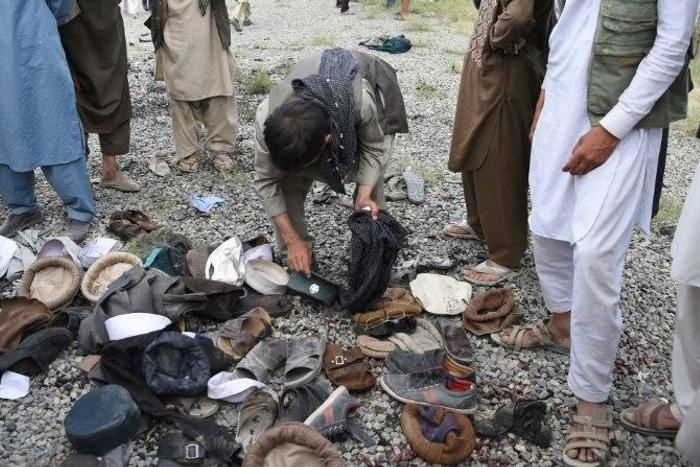 Afghan men examine the belongings of blast victims at the site of a series of explosions that targeted a funeral of a politician's son, who was killed during an anti-government protest a day earlier in Kabul