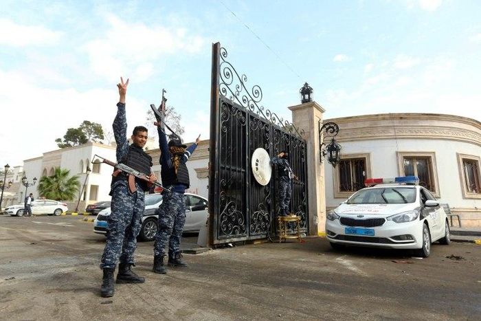 Libyan security forces flash victory signs outside the Guest Palace, a complex of luxury villas in central Tripoli on March 15, 2017