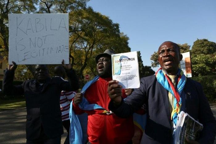 Anti-President Kabila protestors shout slogans and wave placards as they demonstrate near the entrance to a presidential guest house in Pretoria on June 24, 2017, where the President of the Democratic Republic of Congo Joseph Kabila and South African p...