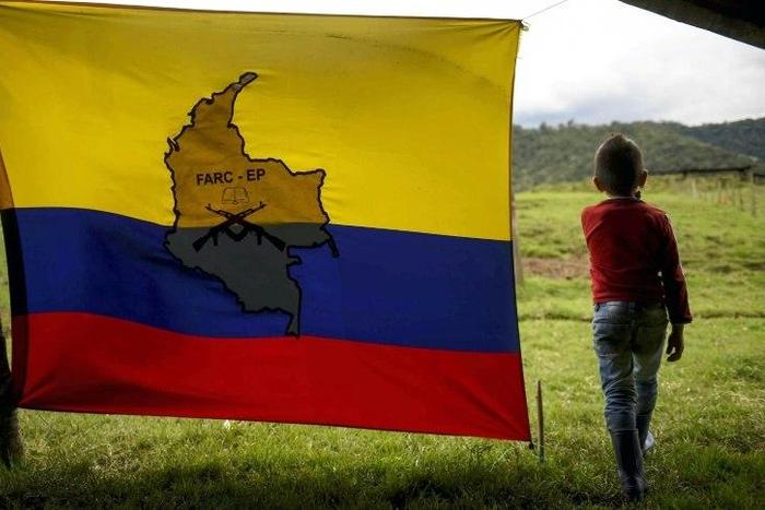 A boy stands next to a FARC-EP flag in the group's birthplace in Marquetalia, center-west Colombia