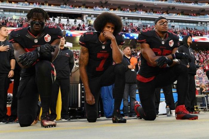 L-R: Eli Harold, Colin Kaepernick and Eric Reid of the San Francisco 49ers kneel during the national anthem prior to an NFL game in 2016