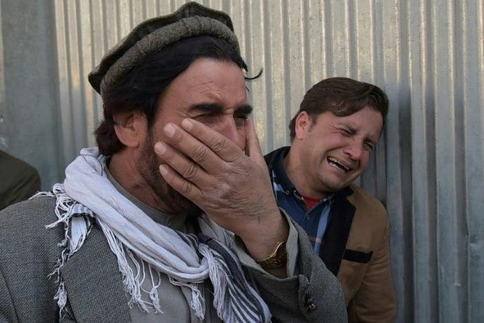 Afghan men weep for their relatives outside the main military hospital in Kabul, on March 8, 2017