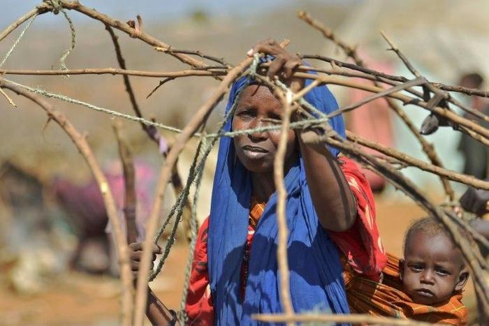 A woman builds a shelter at a makeshift camp on the outskirts of Baidoa, in the southwestern Bay region of Somalia