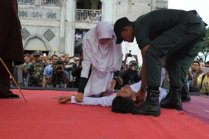 An Acehnese man collapses as he is caned by a religious officer in Banda Aceh on 27th February 2017