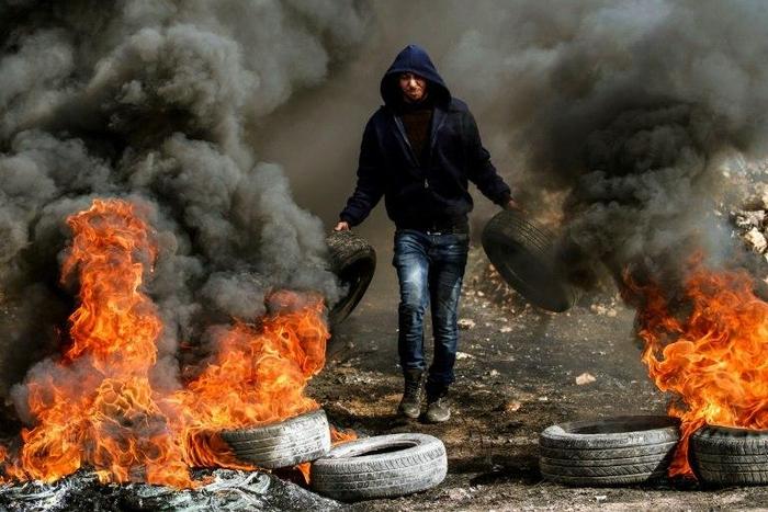 A Palestinian protester burns car tyres during clashes with Israeli security forces near Nablus, in the occupied West Bank, on January 13, 2017
