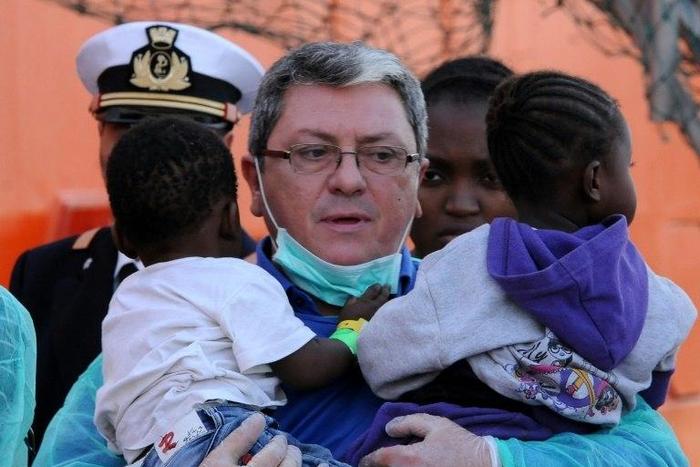 A rescuer holds two young children as migrants disembark from the Siem Pilot on October 24, 2016 in Palermo after rescue operations